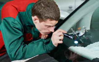Auto car glass repair technician injecting resin into a windshield chip